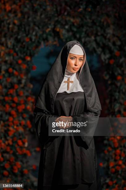 a beautiful brunette nun in a secret rose garden setting - zuster stockfoto's en -beelden