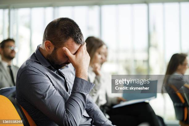 businessman having a headache on a seminar in board room. - boring meeting stock pictures, royalty-free photos & images