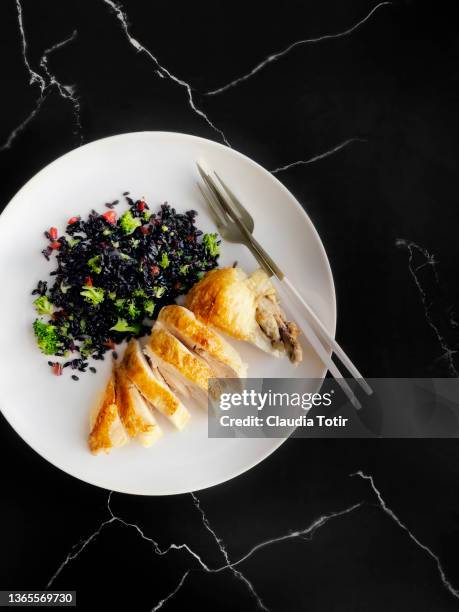 plate of fried black rice with vegetables and roasted chicken breast on marble, black background - black rice imagens e fotografias de stock