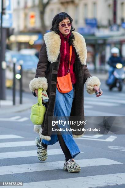 Guest wears sunglasses from Chanel, a burgundy fluffy zipper high neck pullover, a brown shiny leather with large white latte sheep collar / wrist /...