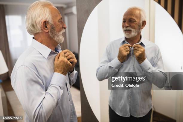 portrait of a senior businessman getting ready for his working day - knäppa knappar bildbanksfoton och bilder