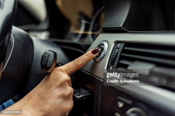 woman finger pressing the start/stop engine button on car - inside car stockfoto's en -beelden