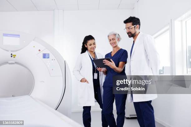 three healthcare workers in conversation in cat scanner room - cat scanner bildbanksfoton och bilder
