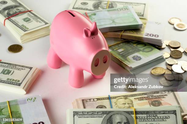 paper currency, dollar bills in bundles on a white background or table. nearby there is a piggy bank in the form of a pink pig. money and coins from different countries. the concept of business and finance, insurance, investment and accumulation of funds. - fajo de billetes de euro fotografías e imágenes de stock