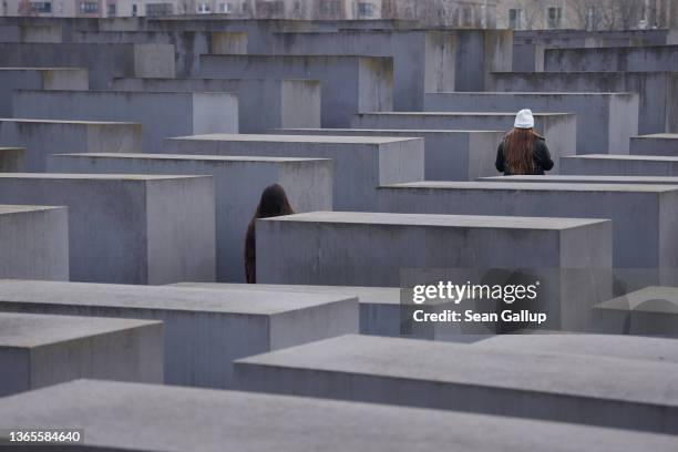 Visitors walk among stelae at the Memorial to the Murdered Jews of Europe, also known as the Holocaust Memorial, on January 19, 2022 in Berlin,...