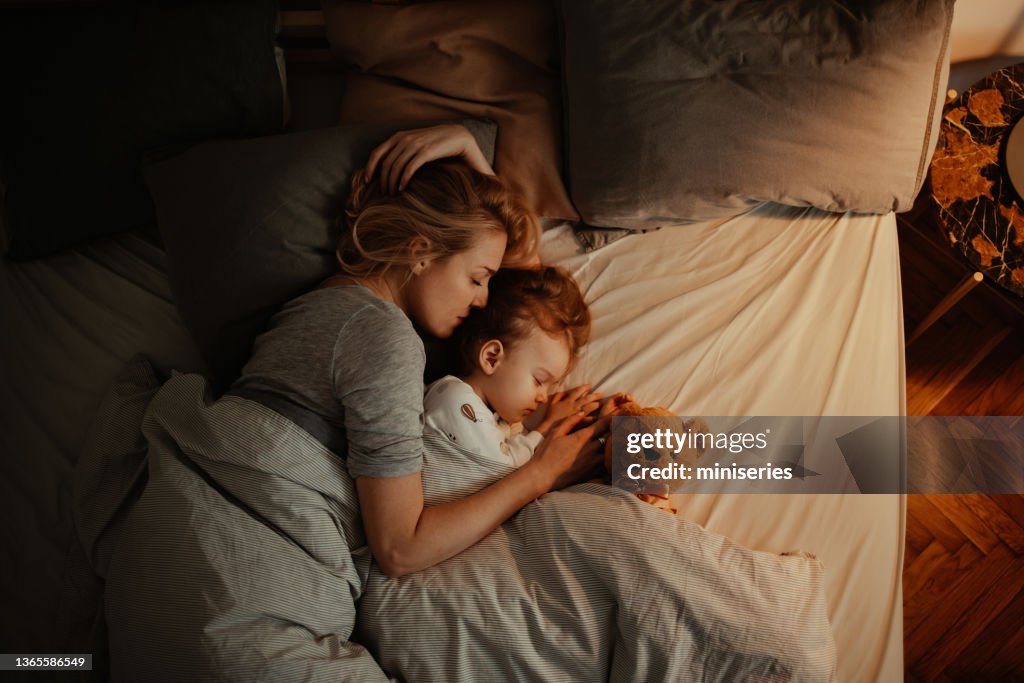 Liebevolle Mutter und Tochter schlafen abends gemeinsam im Bett