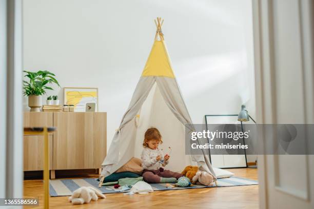 entzückendes mädchen, das zu hause im tipi-zelt spielt - tipi stock-fotos und bilder