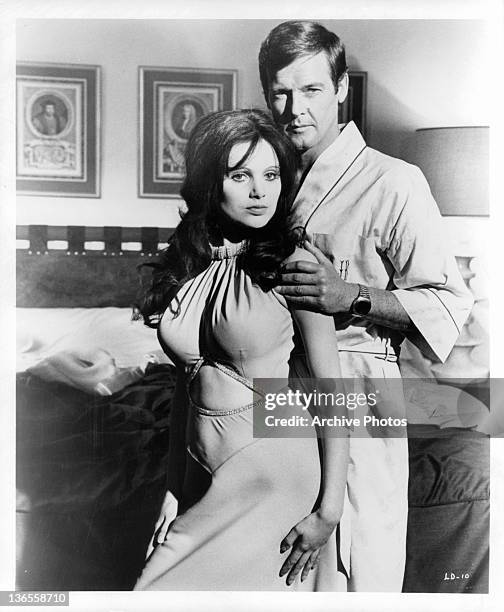 Madeline Smith leaning against Roger Moore in a suggestive manner as he touches her arm in a scene from the film 'Live And Let Die', 1973.