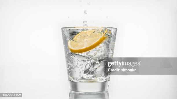 slice of lemon falling into a glass of sparkling water - fizz bildbanksfoton och bilder