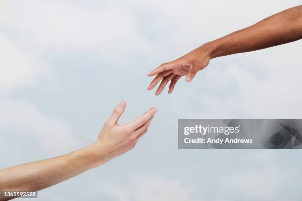 two men reaching out to each other - manos fotografías e imágenes de stock