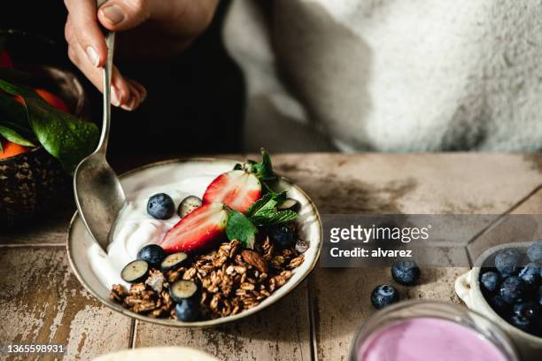 nahaufnahme einer frau, die ein gesundes frühstück isst - granola stock-fotos und bilder