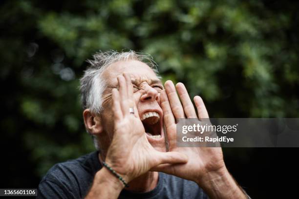 hear this! mature man cups his hands and shouts, mouth wide open - gritar imagens e fotografias de stock
