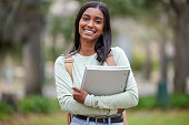 Portrait of a young woman carrying her schoolbooks outside at college