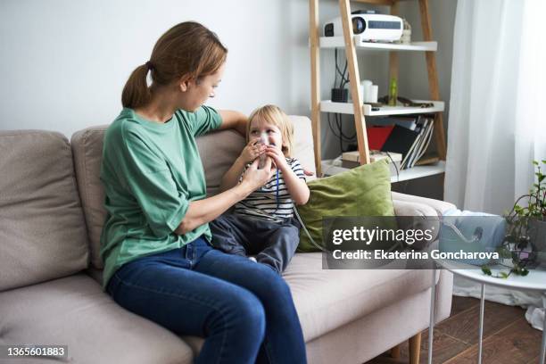 a young mother gives an inhalation to a child. - apparecchio per la respirazione foto e immagini stock