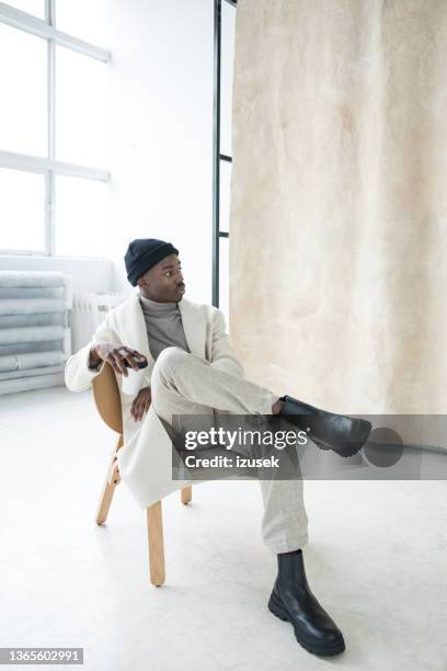 elegant young man wearing white winter coat - black boot stock pictures, royalty-free photos & images