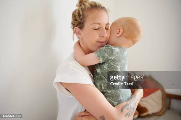 shot of a beautiful young woman holding her baby boy at home - beautiful blonde babes stock pictures, royalty-free photos & images