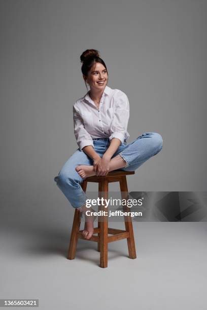 plan de studio d’une belle jeune femme assise sur une chaise sur fond gris - tabouret photos et images de collection