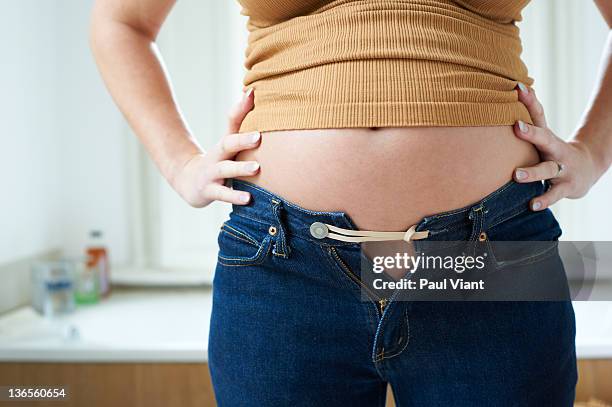 pregnant woman bursting out of jeans - women abdomen stock pictures, royalty-free photos & images