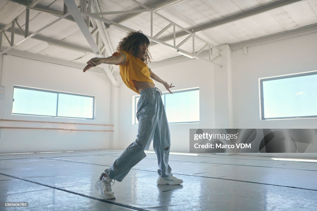 Ganzkörperaufnahme einer attraktiven jungen Hip-Hop-Tänzerin, die in ihrem Studio übt