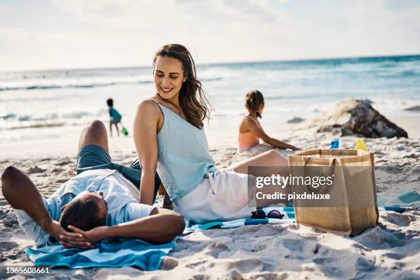 shot of a young couple spending the day at the beach - strandhanddoek stockfoto's en -beelden