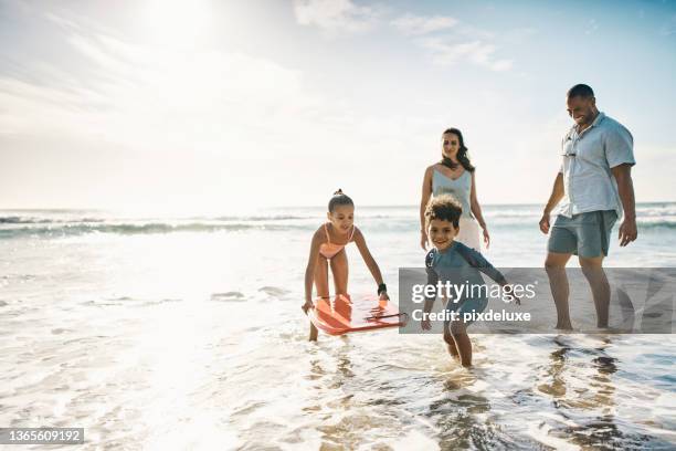 foto de una joven pareja y sus dos hijos pasando el día en la playa - bodyboard fotografías e imágenes de stock