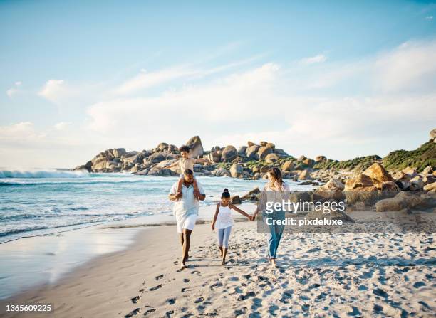 shot of a young couple and their two kids spending the day at the beach - coastal feature stock pictures, royalty-free photos & images