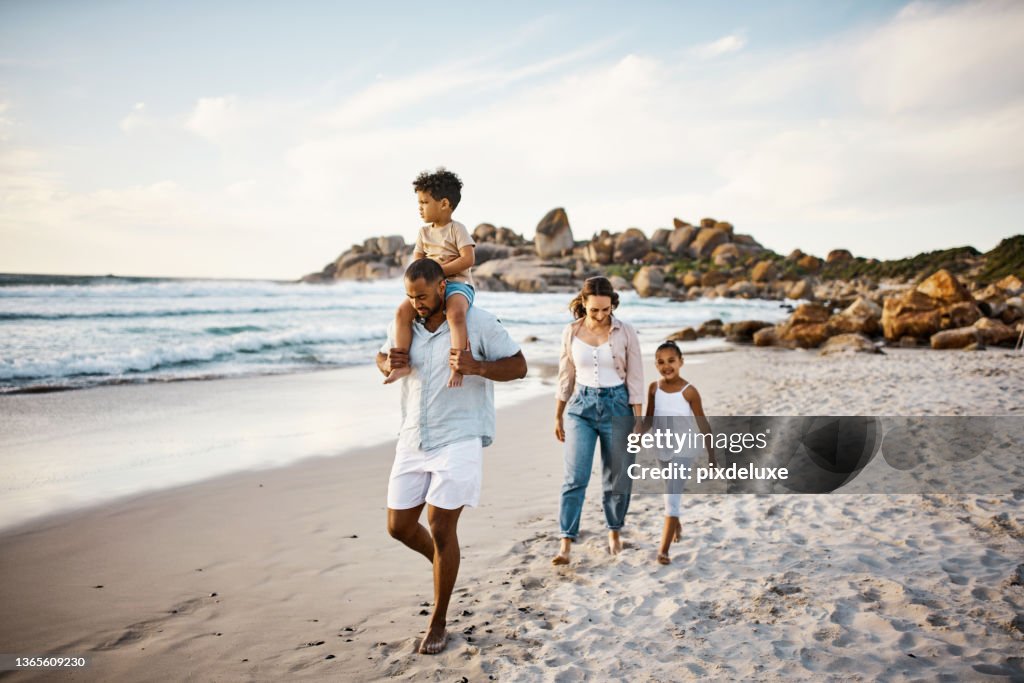 Scatto di una giovane coppia e dei loro due figli che trascorrono la giornata in spiaggia