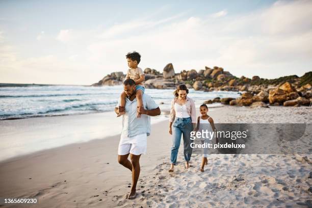 shot of a young couple and their two kids spending the day at the beach - släkt bildbanksfoton och bilder