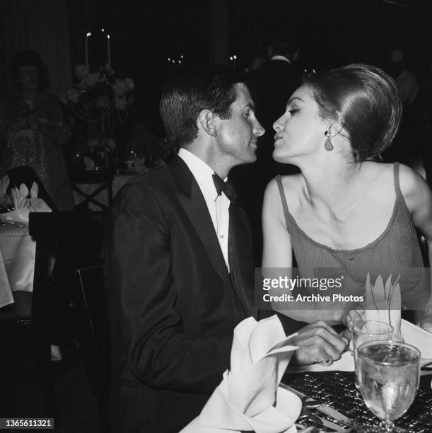 American actors George Hamilton and Julie Newmar kissing at a party for the film 'Carpetbaggers', USA, 1964.
