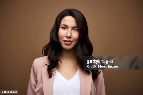 confident businesswoman against brown background - brown blazer 個照片及圖片檔