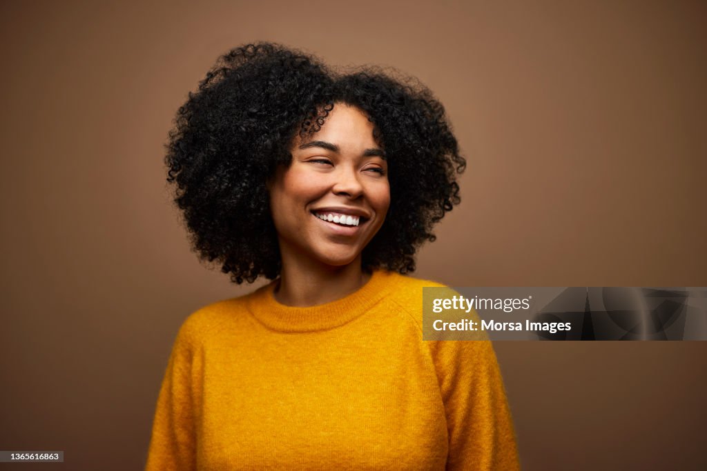 Happy Woman With Curly Hair against Brown Background