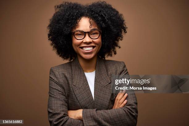 happy businesswoman against brown background - black blazer foto e immagini stock