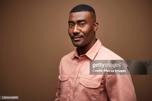 confident black male entrepreneur against brown background - male portrait waist up stock pictures, royalty-free photos & images