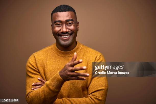 cheerful man in sweater against brown background - formeel portret stockfoto's en -beelden