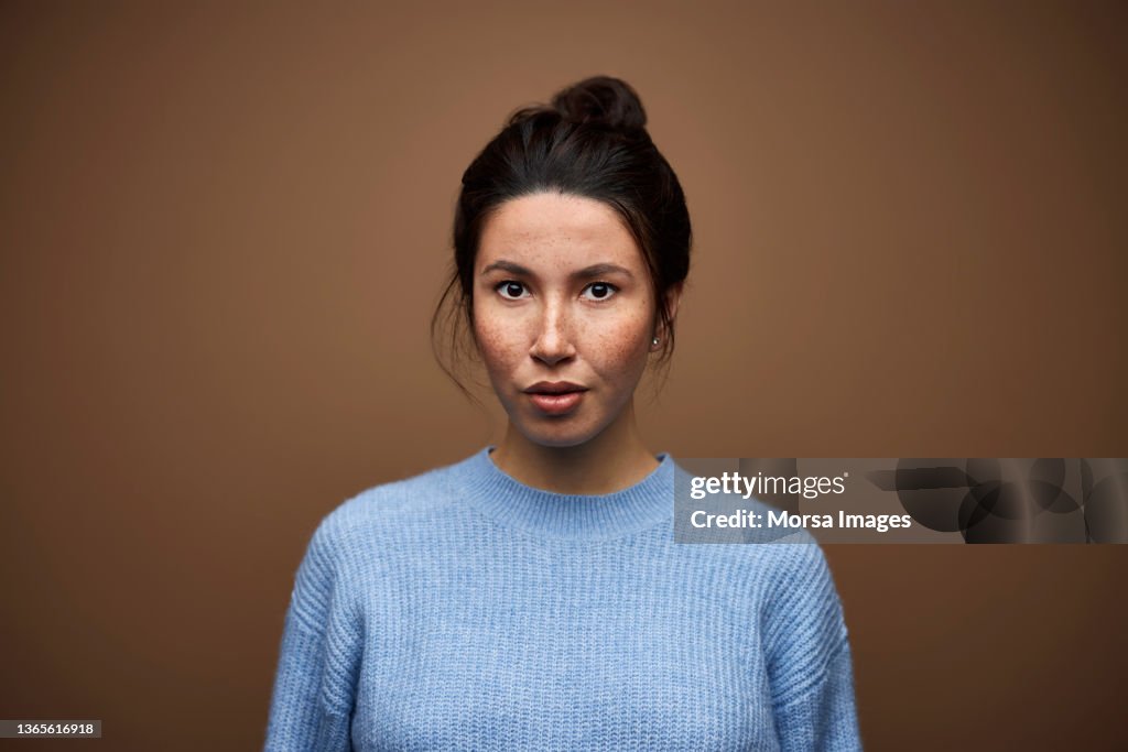 Confident Mixed Race Woman against Brown Background