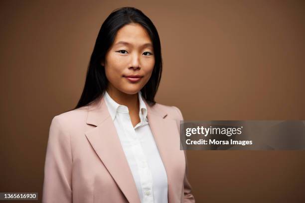 confident young businesswoman in pink blazer - brown background stock pictures, royalty-free photos & images