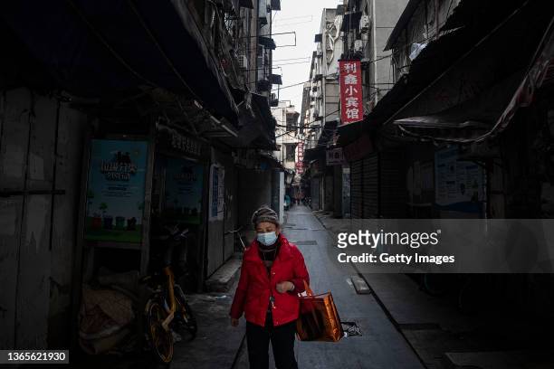 Woman wears a mask while walking down an alleyway on January 19, 2022 in Wuhan, Hubei Province, China. Life for many of the residents in Wuhan is...