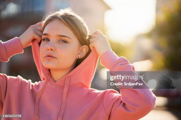 teenager-mädchen, das ihre kapuze anpasst - kapuze stock-fotos und bilder