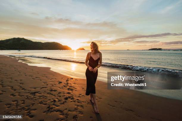 woman enjoying sunset at del coco beach, guanacaste province, costa rica - guanacaste beach stock pictures, royalty-free photos & images