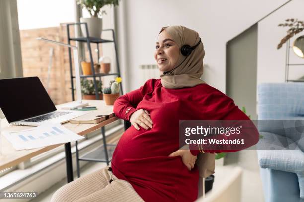 smiling pregnant businesswoman freelancing at home - pregnant muslim stock pictures, royalty-free photos & images