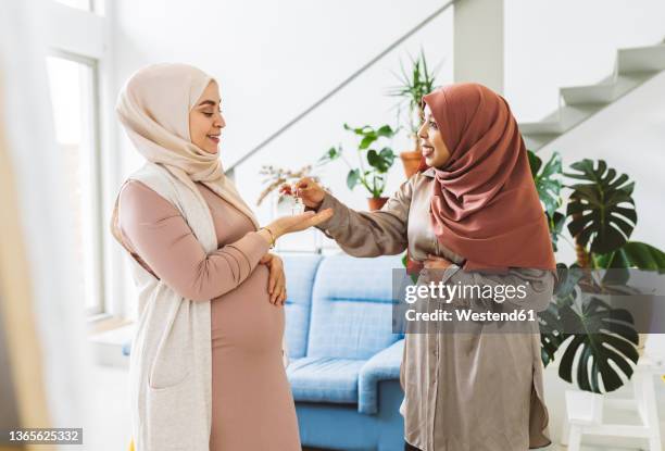 real estate agent giving house key to pregnant woman in apartment - pregnant muslim stockfoto's en -beelden