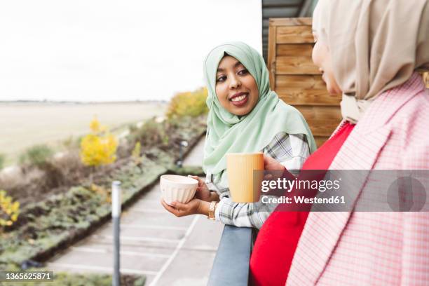 woman talking with pregnant friend in balcony - arabische frau kopftuch stock-fotos und bilder