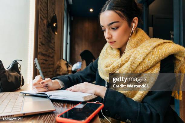 teenager writing in diary and listening music through earphones - digital native stock-fotos und bilder