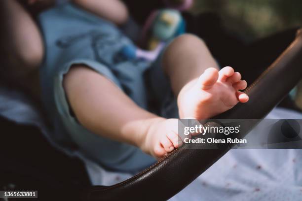 baby in stroller touching handle with his feet. - carrinho de criança imagens e fotografias de stock