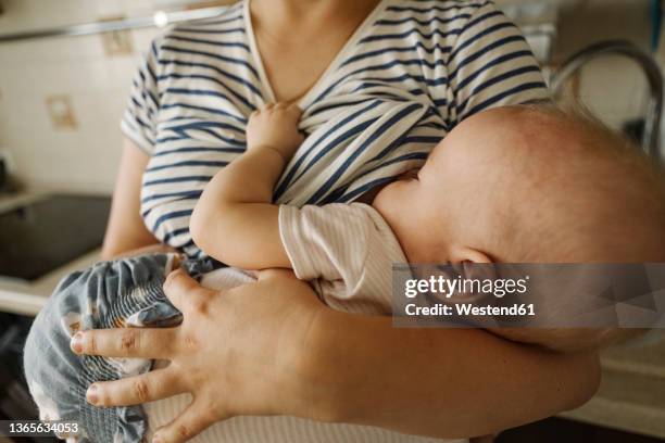 mother's carrying toddler and breastfeeding at home - film still stock-fotos und bilder