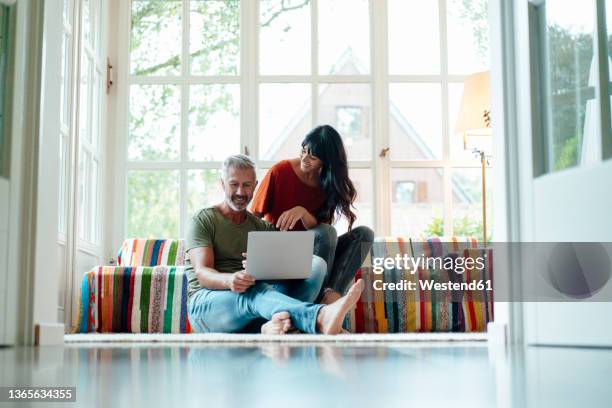 man using laptop by woman at home - 40s laptop stockfoto's en -beelden