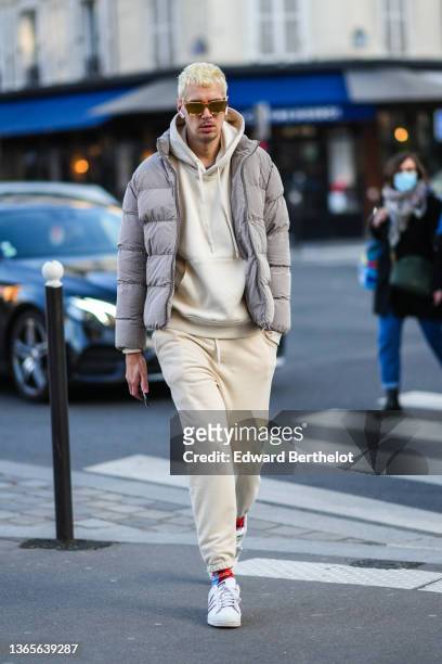 Guest wears gold sunglasses, a pale yellow hoodie sweater, matching pale yellow sport pants, a gray high neck puffer jacket, red / blue / orange...