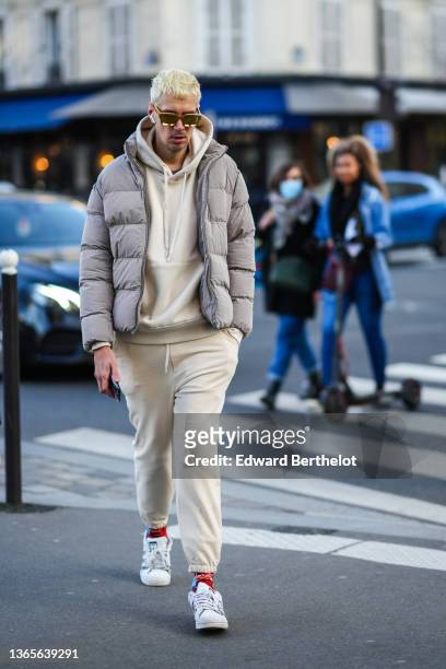 Guest wears gold sunglasses, a pale yellow hoodie sweater, matching pale yellow sport pants, a gray high neck puffer jacket, red / blue / orange...