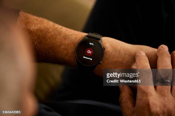 man measuring body functions on smart watch at home - activity tracker stock pictures, royalty-free photos & images