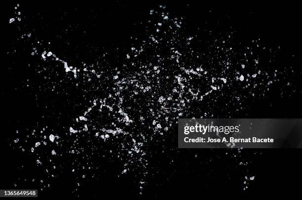 drops and splashes of water floating in the air on a black background. - splash stock pictures, royalty-free photos & images